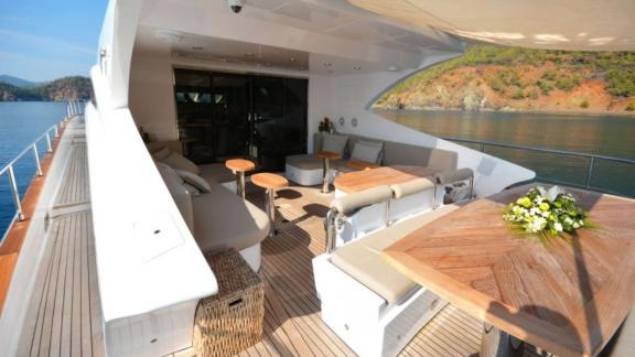 Stylish outdoor area of a luxurious motor yacht with seating and dining table.