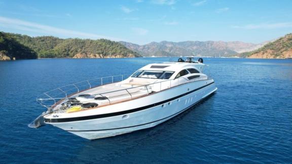 Modern motor yacht in the clear waters of the Aegean Sea off the green coast.