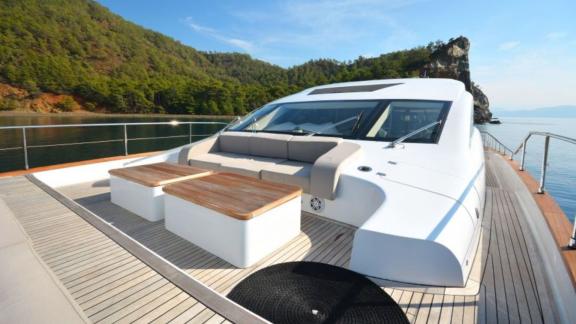 Elegant sun deck of a luxurious motor yacht with a green coastal backdrop.