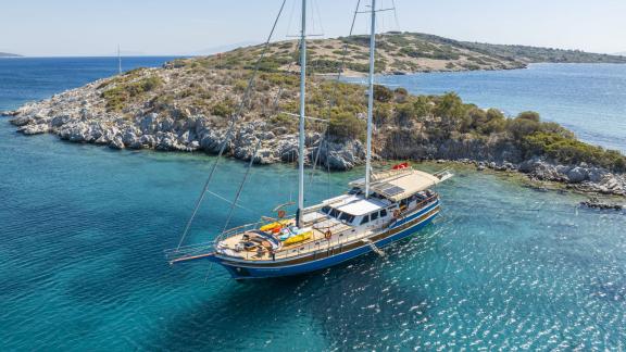 Gulet Gozdem The One anchored in clear blue waters near Bodrum, surrounded by rocky islands and green countryside.