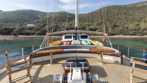 Deck der Gulet Gozdem The One mit Sitzgelegenheiten und Blick auf die grüne Küste von Bodrum, klares Wasser, sonniger Ta