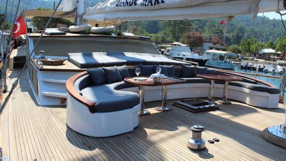 Spacious sun deck of the Grande Mare with elegant lounge, set table and view of the harbour, ideal for luxury charters i