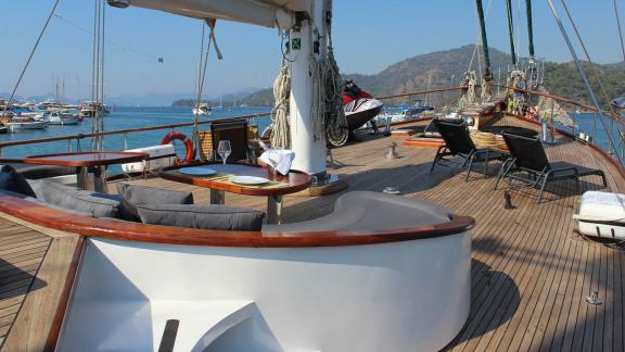 Elegantes Deck der Grande Mare mit komfortabler Sitzlounge, gedecktem Tisch und Sonnenliegen, perfekt für Yachtcharter i