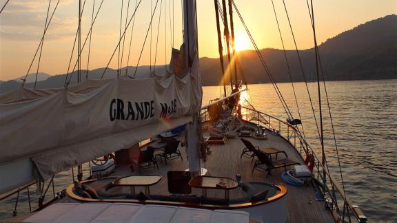 Das Deck der Grande Mare bei Sonnenuntergang, umgeben von ruhigem Wasser und Bergen.