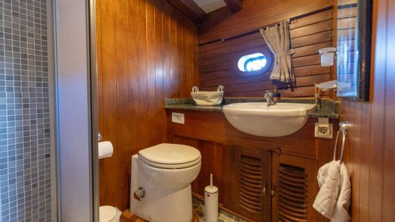 Stylish bathroom on the Serenad yacht with wood paneling, sink, and toilet.