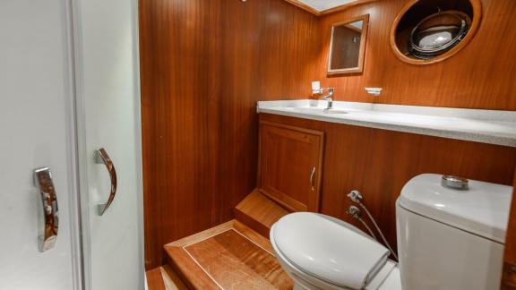 Modern bathroom with wood paneling on the Gulet Anıl Kaptan 1, equipped with a shower and toilet.