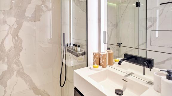 Şık duş ve lavabo ile donatılmış modern banyo, Katamaran Above & Beyond'da.