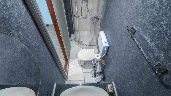 Compact bathroom with shower, toilet, washbasin and grey wall panelling.