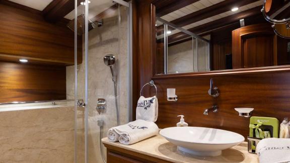 Elegant bathroom with wood panelling, modern shower, washbasin and high-quality towels.