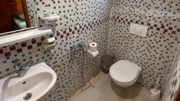 Compact bathroom on Gulet Avuncan with colorful mosaic tiles, sink, and toilet.