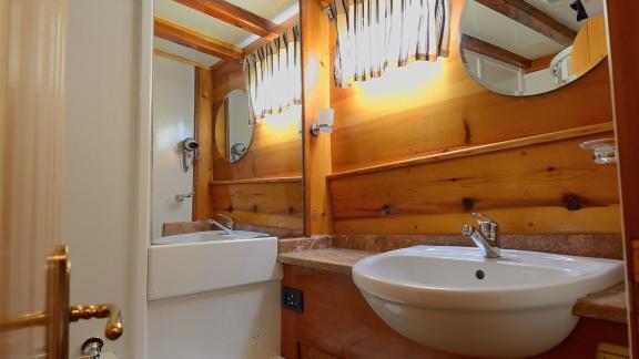 Modern bathroom of Gulet Xenos 2 in Bodrum with elegant wood paneling and comfortable amenities.