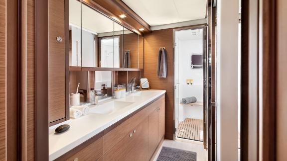 Elegant bathroom with double sink, large mirrors, and separate shower cabin in Emerald Gemini catamaran.