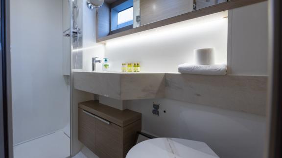 Lavabo, ayna, duş ve doğal ışık için küçük bir pencereye sahip iyi donanımlı banyo.