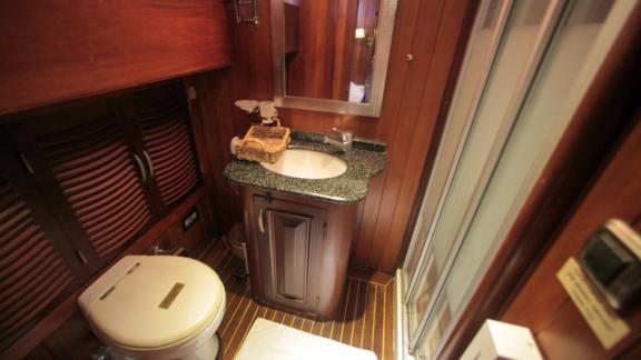 A stylish bathroom on board the Gulet Dulcinea with elegant wood panelling, a modern shower and a washbasin with a grani