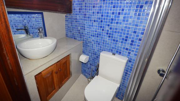 Badezimmer mit blauen Mosaikfliesen, Waschbecken und Dusche auf einer Gulet.