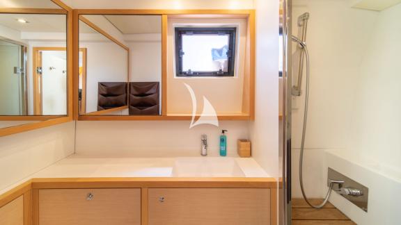 Bright bathroom with vanity, window, and separate shower cabin, designed in warm wood tones.