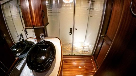 Luxurious bathroom on a sailing yacht with elegant wood panelling, a modern washbasin and a spacious shower cubicle.