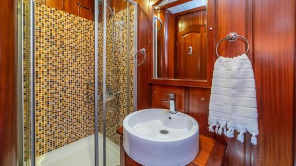 Elegantes Badezimmer mit Duschkabine, Mosaikfliesen und stilvollem Waschbecken auf einem luxuriösen Gulet in Bodrum.