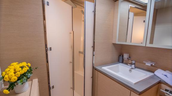 Modern bathroom on a catamaran with a large sink area, mirrors, and a separate shower cabin.