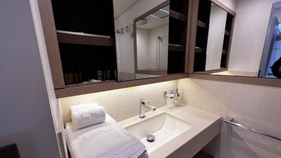 Compact, modern bathroom featuring a large vanity and mirrors, offering additional storage space.