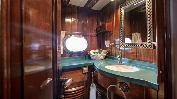 Elegant bathroom on the gulet Entre Cielos with wooden fittings, modern washbasin and maritime accents.