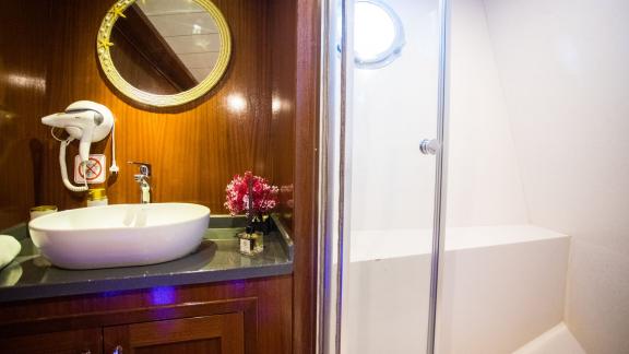 A stylish bathroom on board the gulet Queen of RTT in Fethiye, equipped with a modern washbasin, a round mirror and a sh