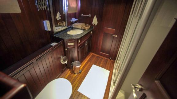 An elegant bathroom on board the Gulet Dulcinea with stylish wood panelling, a modern washbasin and a shower.