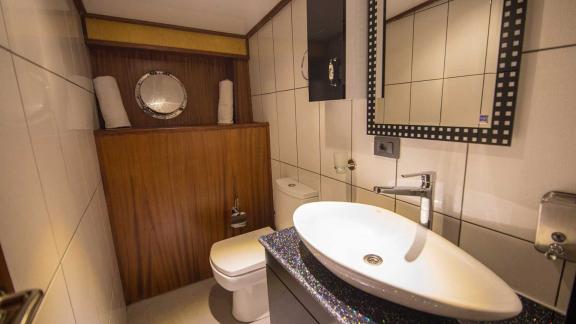 Nevra Queen'de modern banyo, şık lavabo ve yuvarlak pencere.