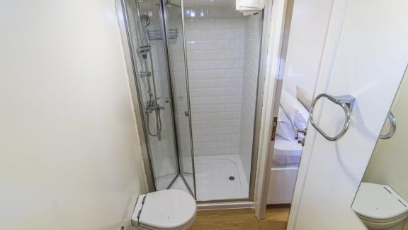 Bathroom with shower, toilet, and large mirror for maximum comfort.