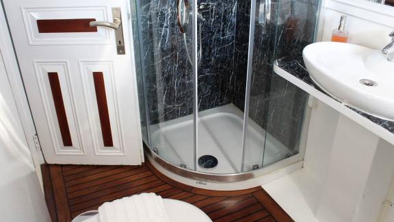 Modern bathroom of the Grande Mare with glass shower, stylish washbasin and elegant wooden design.