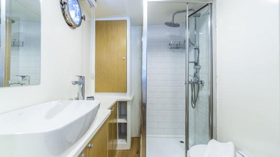 Modern bathroom with large shower, stylish sink, and ample storage space.