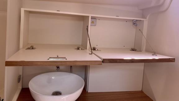 The bathroom of the Aldebaran sailing yacht features a sink and top-opening cabinet doors.