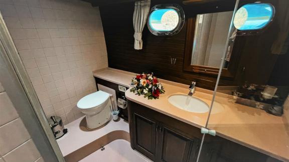 An elegant bathroom on a sailing ship, equipped with modern amenities, a window and decorative flowers.