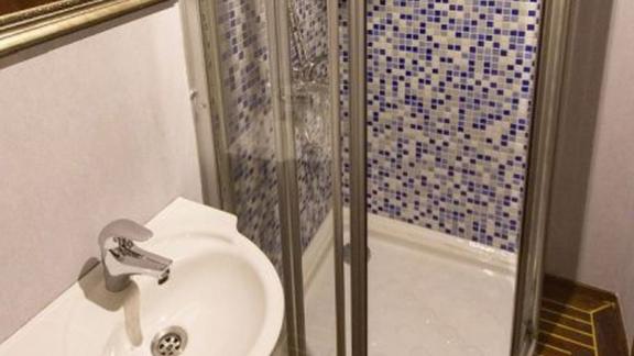 Badezimmer mit Duschkabine und blauen Mosaikfliesen.