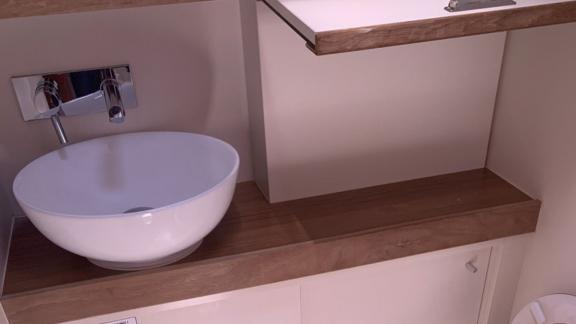 The bathroom of the sailing yacht Baxter features a stylish white sink with wooden shelves.