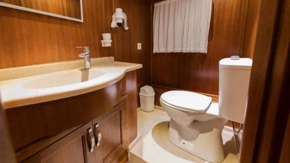 The bathroom on gulet Seven 1 offers a simple and comfortable space with warm wooden details and modern fixtures.