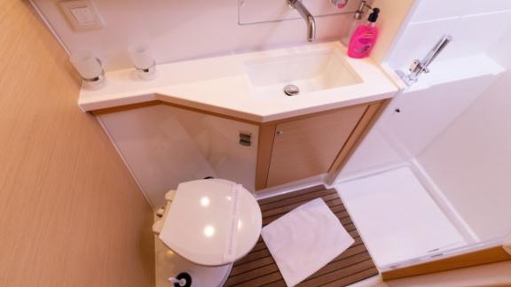 Compact bathroom in the Saelma Lagoon 450 with a toilet, sink, and separate shower.