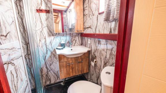 Bathroom of Gulet Esperanza featuring marble-patterned walls, a shower cabin, a sink, and a toilet.