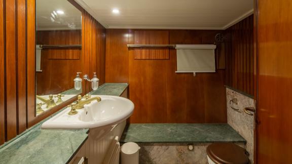 Elegant bathroom with wood panelling, marble washbasin and modern fittings.