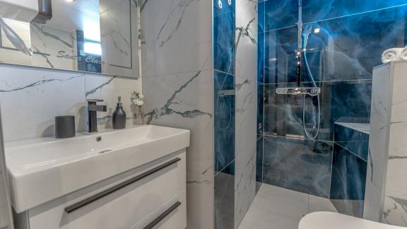 Modern bathroom with marble walls and spacious shower.