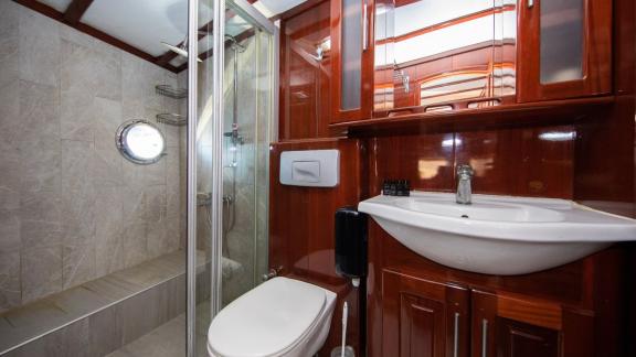 Gulet Vivere'de zarif ahşap mobilyalar, duş ve şık armatürlerle donatılmış modern banyo.