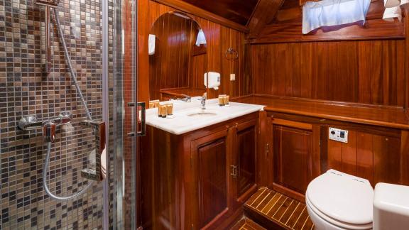 The bathroom of gulet Croatia offers a luxurious experience with wooden details, a modern shower, and a spacious sink ar