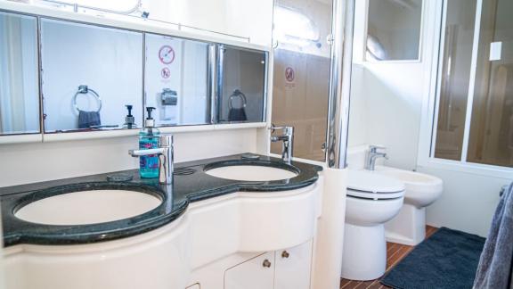 The bathroom on Alfa F yacht features two sinks, large mirrors, and modern fixtures.