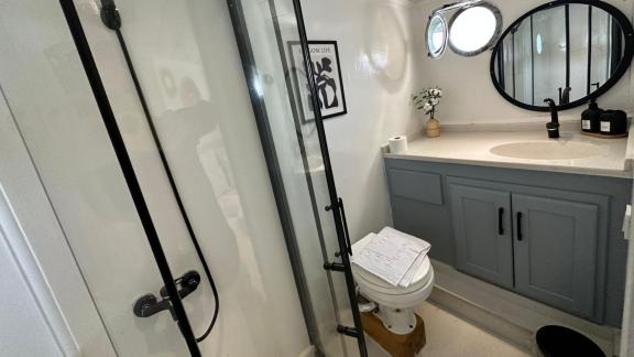 Elegant bathroom with shower, round mirror, and porthole on Gulet Bohemian.