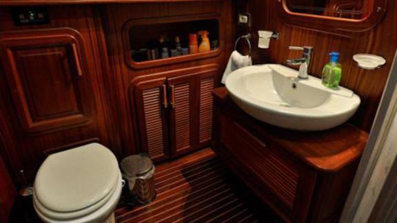 Elegant bathroom with sink, toilet, and wooden cabinets on Gulet Mikado.