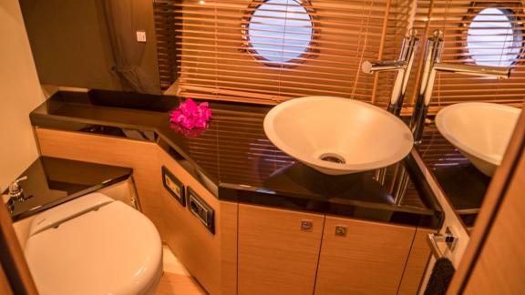 The motor yacht Carmencita la Grande's bathroom features a modern sink, large mirror, and small window.