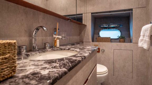 The modern bathroom of Dark Knight features elegant marble details and a window for natural light.