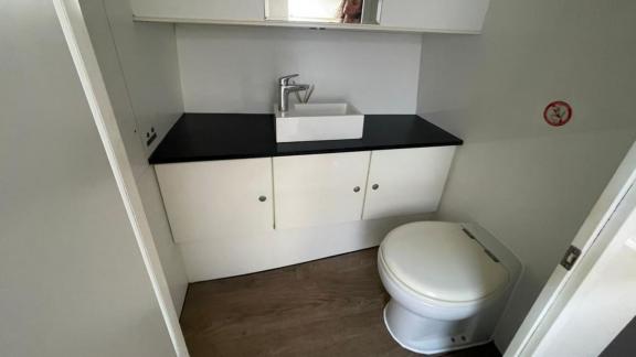 The modern bathroom of the Tequila motor yacht features a minimalist design with a sink and white cabinets.