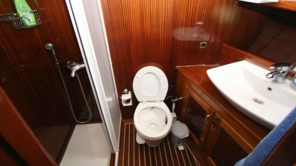 Compact bathroom on Gulet Miramare with wood paneling, shower, toilet, and sink.