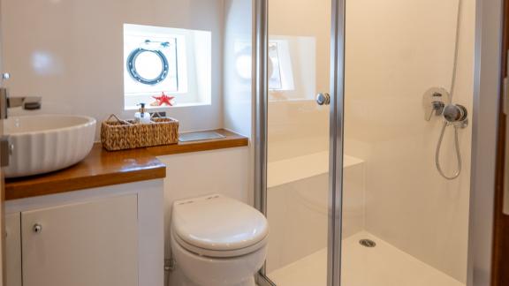 The bathroom on the Gottiri motor yacht features a compact shower and a modern sink.